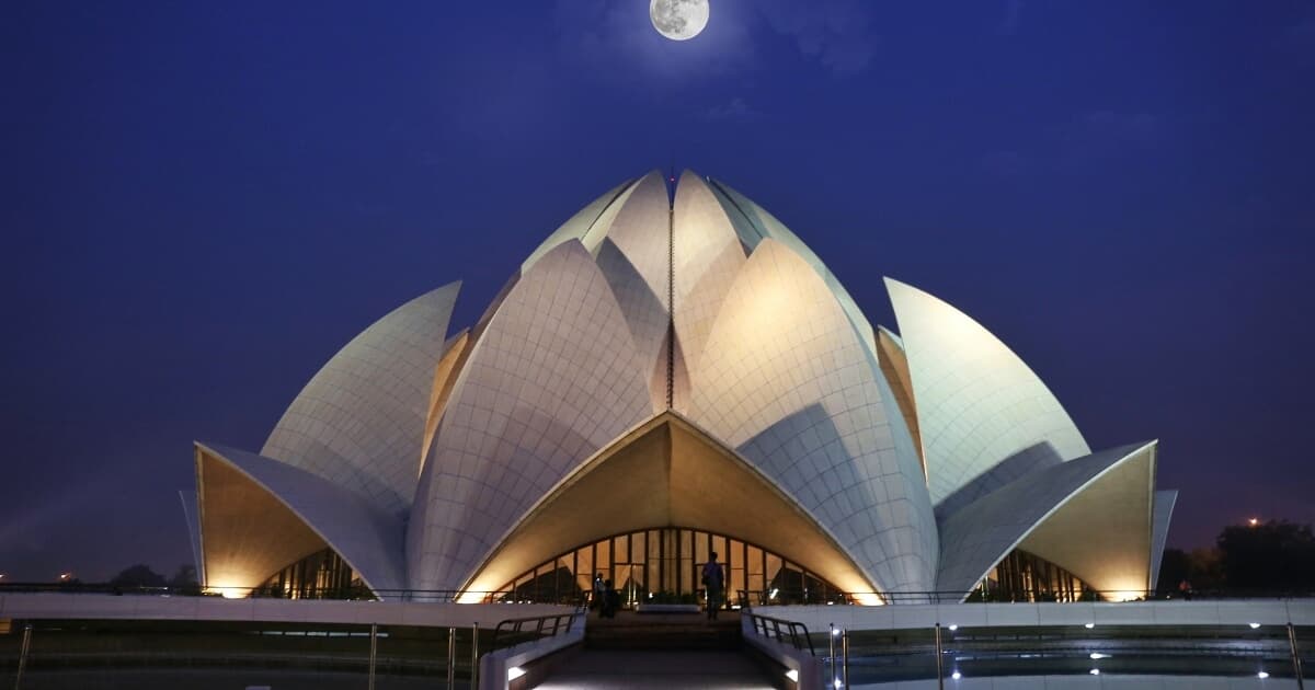 Lotus Temple in Delhi illuminated at night under a full moon