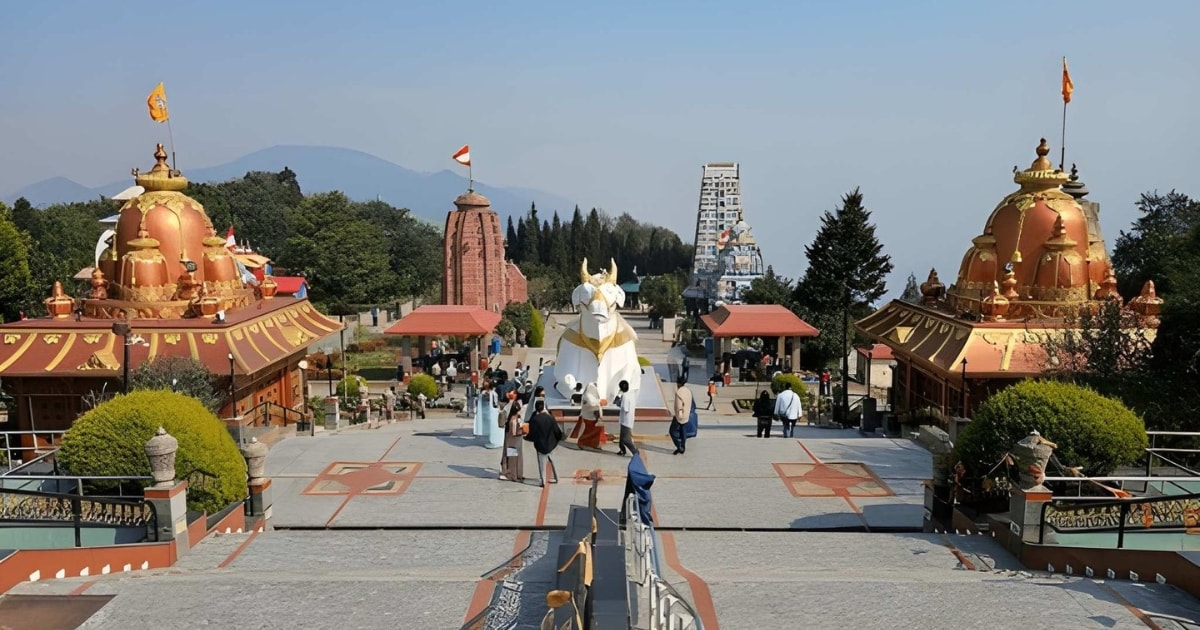 Visitors exploring the sprawling courtyard of Siddhesvara Dham, also known as Char Dham in Namchi, Sikkim, featuring beautiful copper-roofed Hindu temple replicas and a prominent white Nandi statue against a Himalayan backdrop.